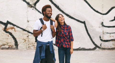 Frau und Mann vor einer Graffitiwand aneinander gelehnt