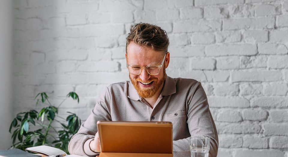 Zufriedener Mann arbeitet am Laptop, symbolisiert digitale Geldanlage oder Investmentberatung
