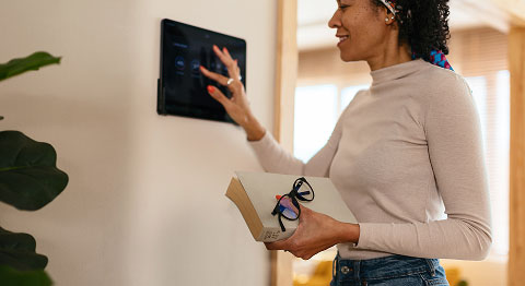 Frau in weißem Oberteil tippt etwas in Panel an der Wand