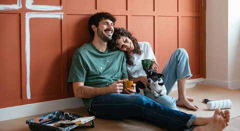 Mann und Frau sitzen an eine Wand gelehnt mit Hund auf dem Boden 