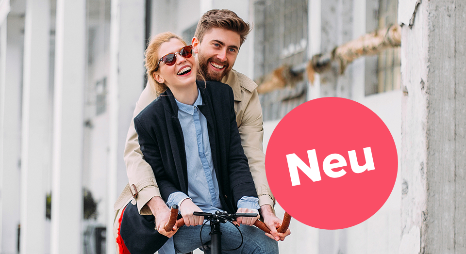 Paar sitzt zusammen auf einem Fahrrad und lacht