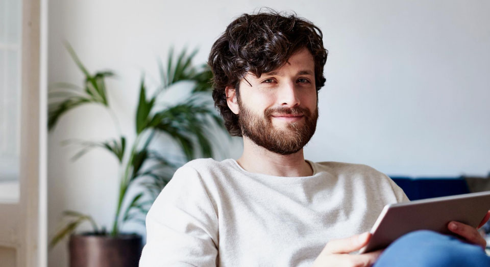 Mann mit Tablet in der Hand lächelt zufrieden