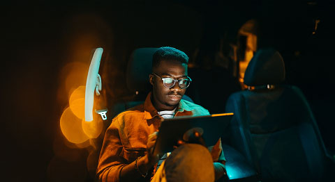 Mann mit Brille tippt in einem Auto an seinem Tablet