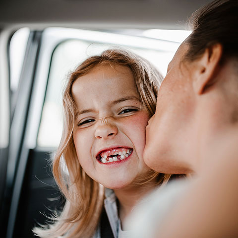 Mädchen mit Zahnlücke lächelt ihr Gegenüber breit an