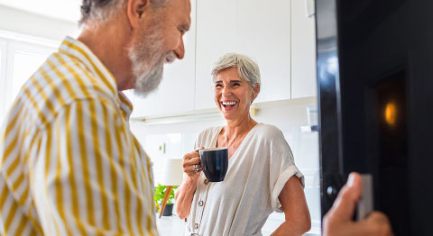 Älteres Ehepaar steht in der Küche und trinkt Kaffee