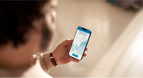 Verschwommender Mann hält Smartphone in der Hand und checkt die Wertentwicklung seiner Wertpapiere