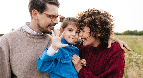 Eltern haben ihr Kind in den Armen und laufen in einer Wiese