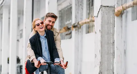 Mann und Frau sitzen lachend zusammen auf einem Fahrrad