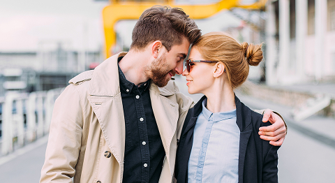 Mann und Frau in Businessklamotten halten sich im Arm und schauen sich innig in die Augen