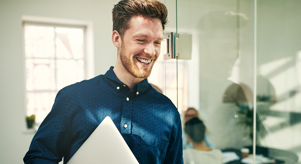 Mann in blauem Hemd hat Laptop unter dem Arm