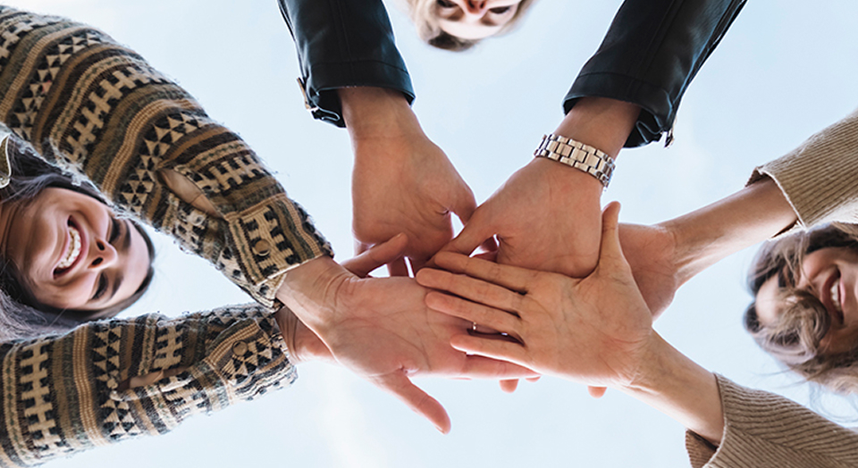 Gruppe von Menschen tut ihre Hände in der Mitte zusammen 