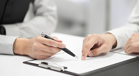 Nahaufnahme von zwei Personen, die zusammen Unterlagen zum Unterschreiben durch gehen