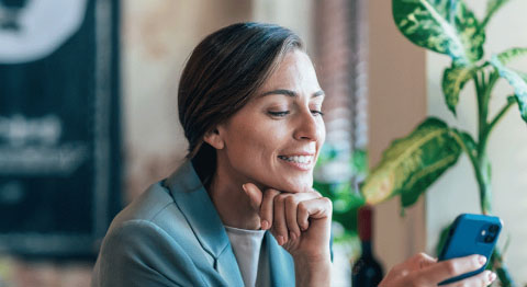 Grauhaarige Frau in grauen Blazer schaut in ihr Smartphone