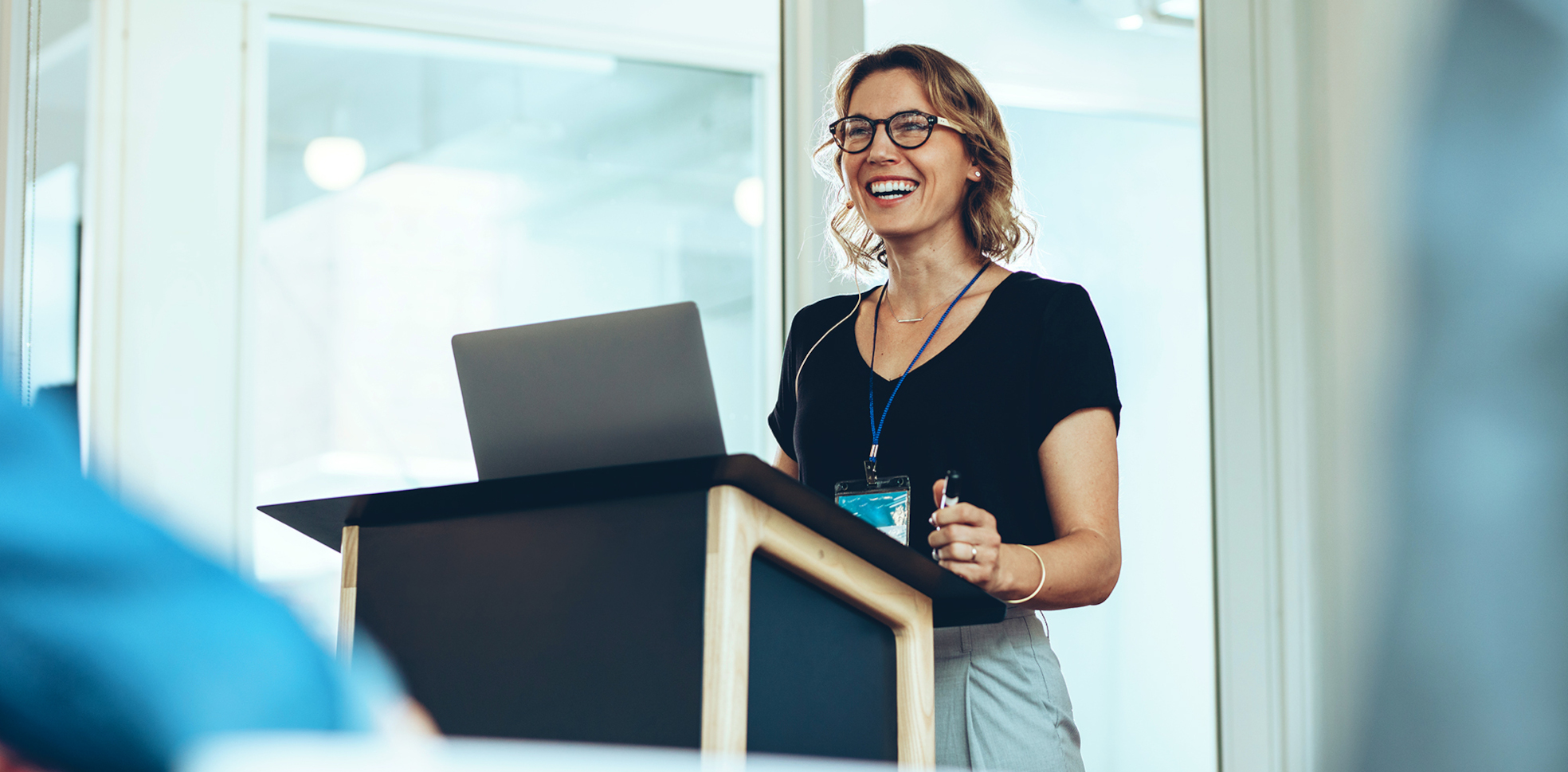 Frau steht am Rednerpult und lächelt 