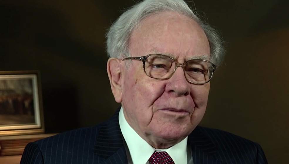 Warren Buffet, Mann mit kurzen grauen Haaren und Brille im blau-weißem Nadelstreifenanzug und roter Krawatte