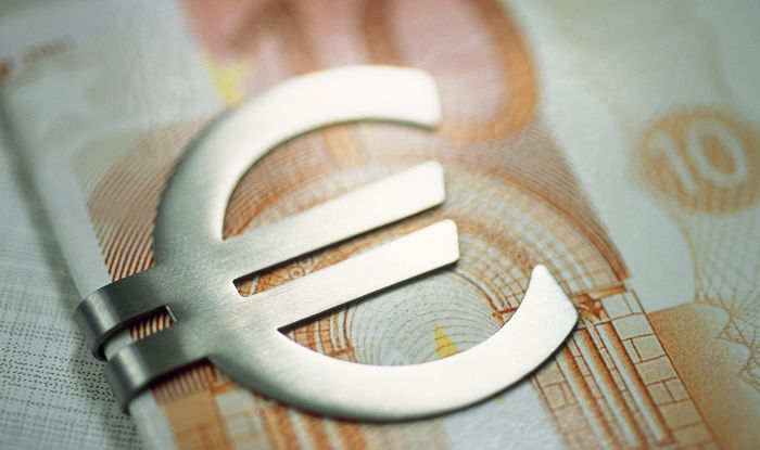 Ausschnitt eines Geldscheins der von einer Geldklammer im Euro-Design gehalten wird