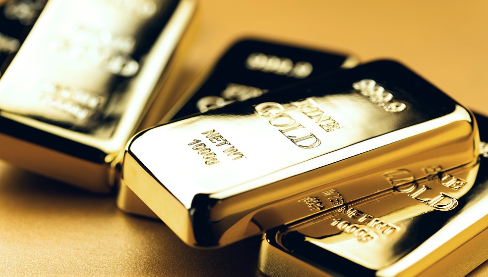 Blick von oben auf einen Tisch auf dem sich mehrere glänzende Goldbarren befinden