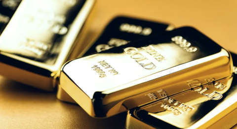 Blick von oben auf vier übereinander liegende glänzende Goldbarren