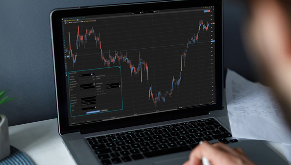 Mann sitzt an seinem Laptop und beobachtet die Kurse