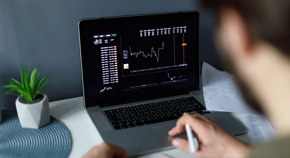 Mann sitzt an seinem Laptop und beobachtet die Kurse