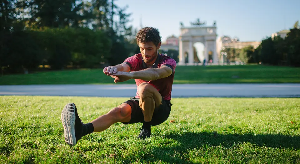 Mann in Sportklamotten treibt Sport auf einer Wiese im Freien