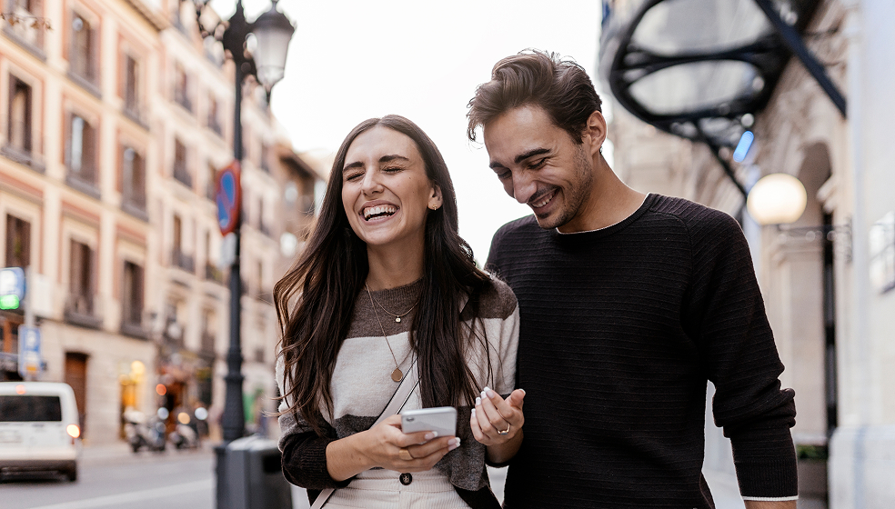 Mann und Frau laufen fröhlich zusammen durch eine Stadt