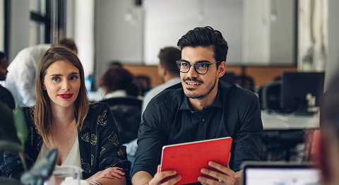 Mann und Frau sitzen in einem Konferenzraum und unterhalten sich in der Gruppe