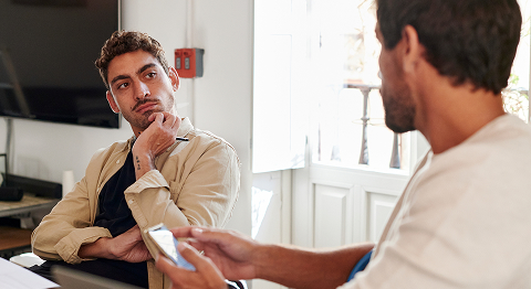 Zwei Männer unterhalten sich in einem Wohnzimmer und schauen sich dabei an