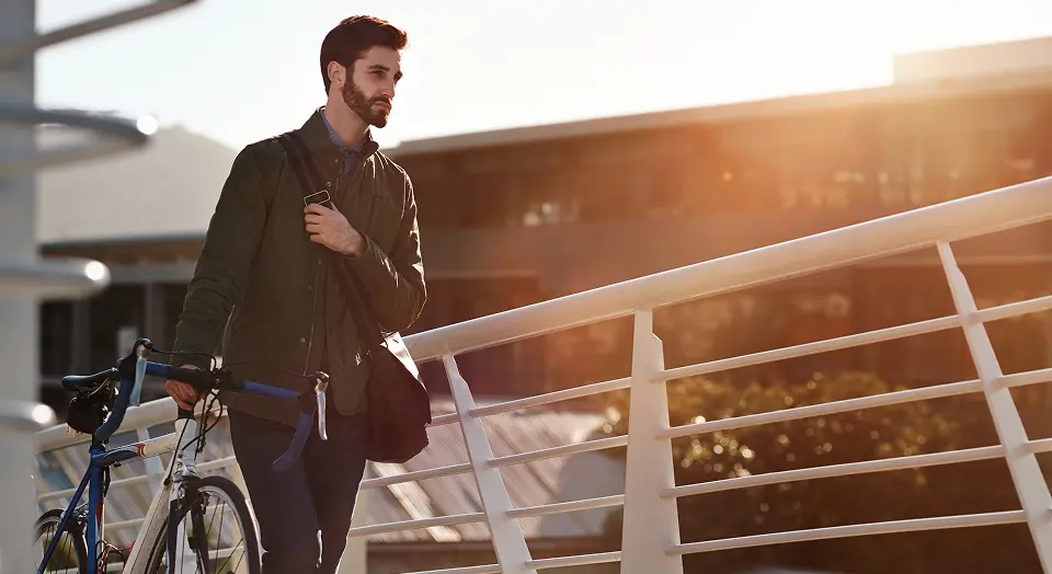 Mann in langen Klamotten läuft draußen auf einer Brücke