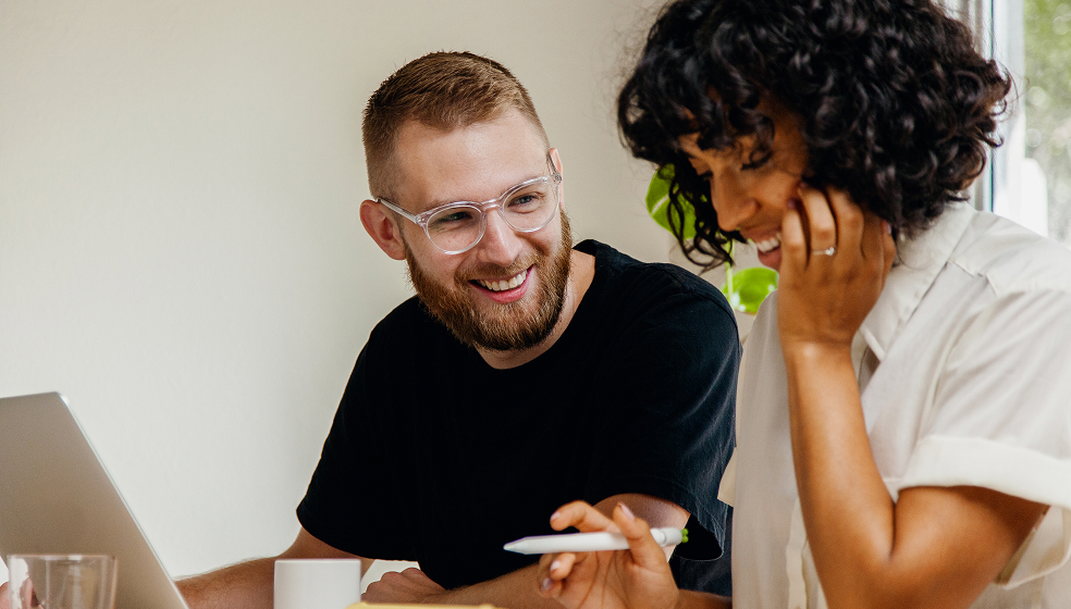 Mann und Frau sitzen gemeinsam am Schreibtisch und machen ihre Steuererklärung am Laptop