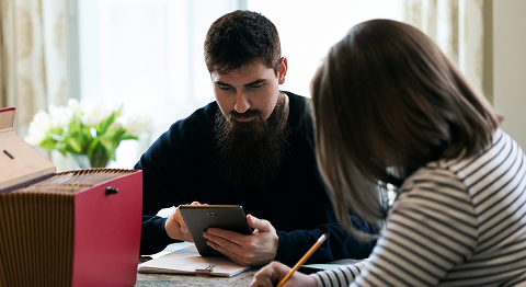 Mann und Frau sitzen an einem Tisch und regeln gemeinsam ihre Steuerangelegenheiten