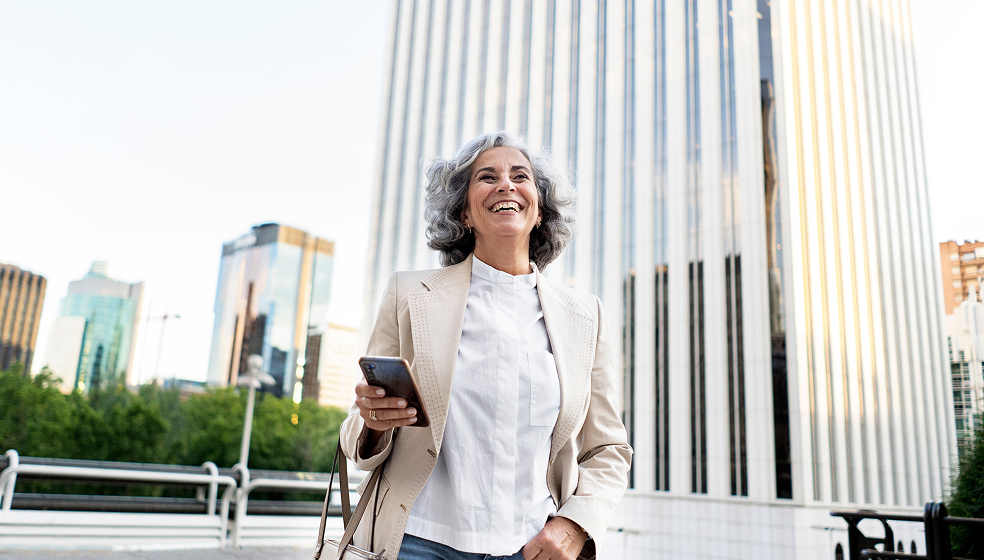 Frau in Blazer läuft glücklich über einen öffentlichen Platz voller Wolkenkratzer