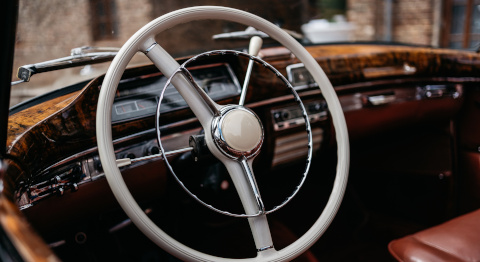 Nahaufnahme eines Oldtimer-Lenkrads mit Chromdetails im Innenraum eines klassischen Fahrzeugs.