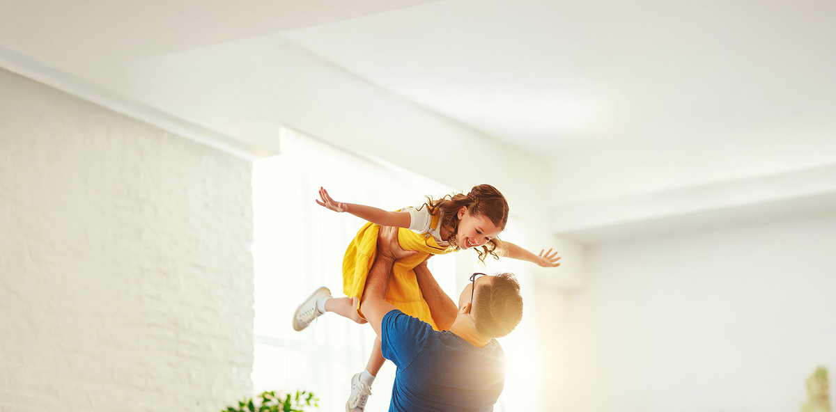 Vater hebt Tochter in die Luft und beide lachen