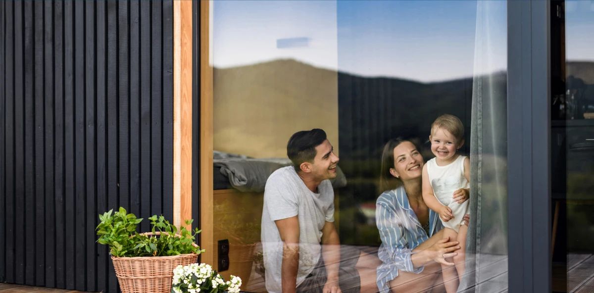 Familie mit Kleinkind sitzen in ihrem Haus an großem Terrassenfenster