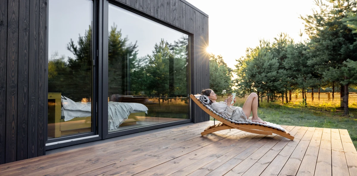 Frau liegt bei Sonnenuntergang auf einer Liege auf ihrer Terrasse