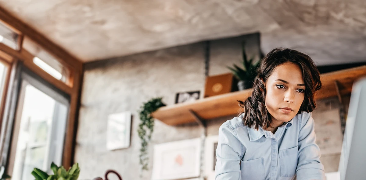 Braunhaarige Frau in Jeansjacke schaut in ihren Bildschirm