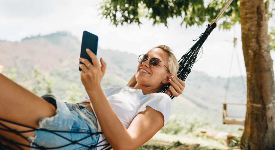 Frau mit Smartphone in Hängematte