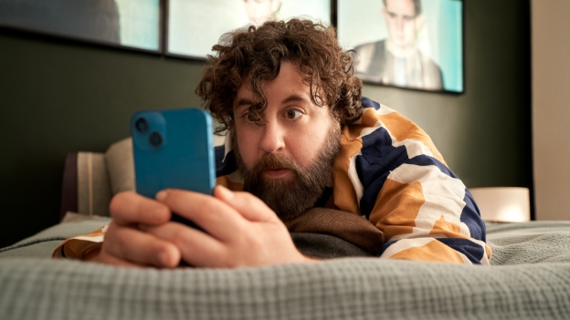 Mann schaut begeistert in sein Smartphone