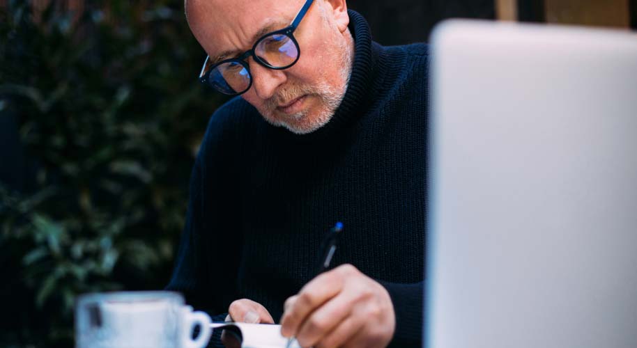 Konzentrierter Mann mit Brille am Schreiben
