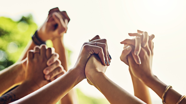 Viele verschiedenfarbige Hände halten sich gegenseitig fest