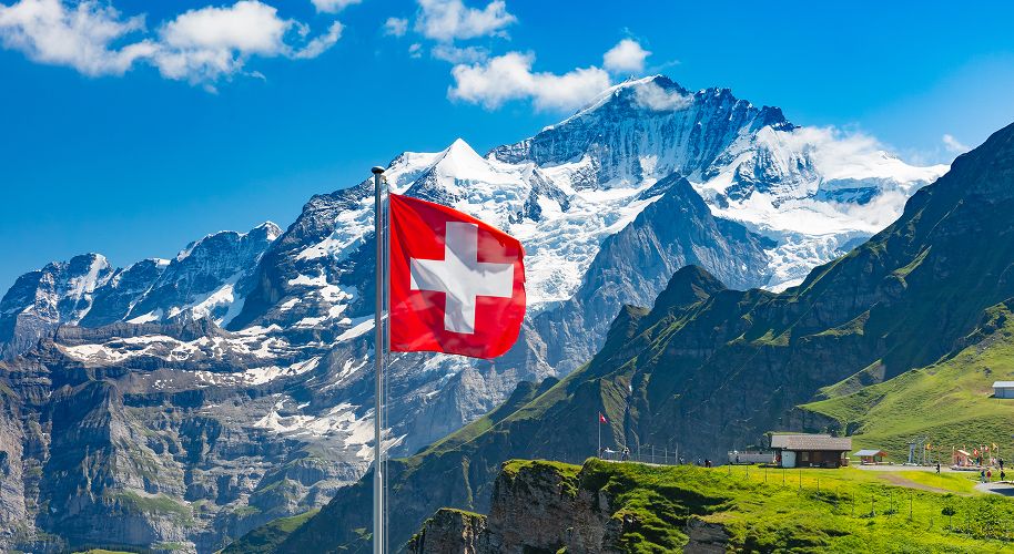 Flagge der Schweiz weht vor Bergen im Wind